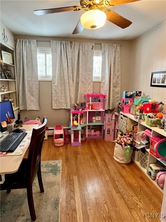 game room with a wealth of natural light, wooden walls, a baseboard radiator, and hardwood / wood-style floors