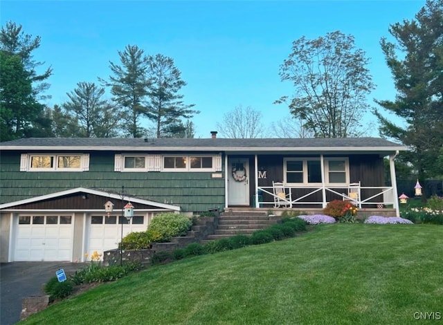 view of front of house featuring a front yard, covered porch, and a garage