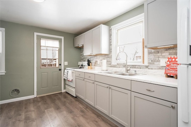 kitchen with decorative backsplash, sink, dark hardwood / wood-style flooring, and white appliances