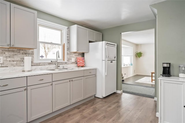 kitchen featuring white fridge, plenty of natural light, light wood-type flooring, and sink