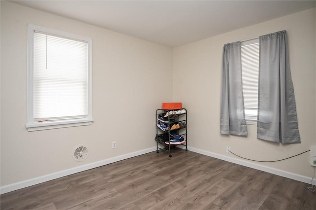 empty room with a healthy amount of sunlight and hardwood / wood-style floors