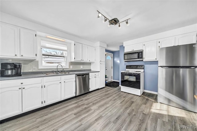 kitchen featuring white cabinets, light wood-type flooring, appliances with stainless steel finishes, and sink