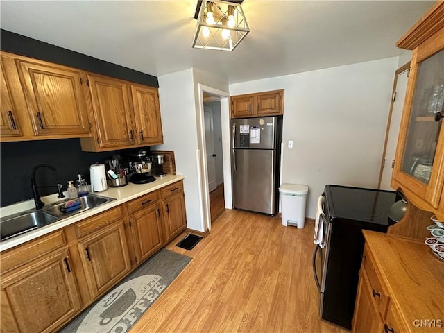 kitchen with sink, appliances with stainless steel finishes, and light hardwood / wood-style flooring