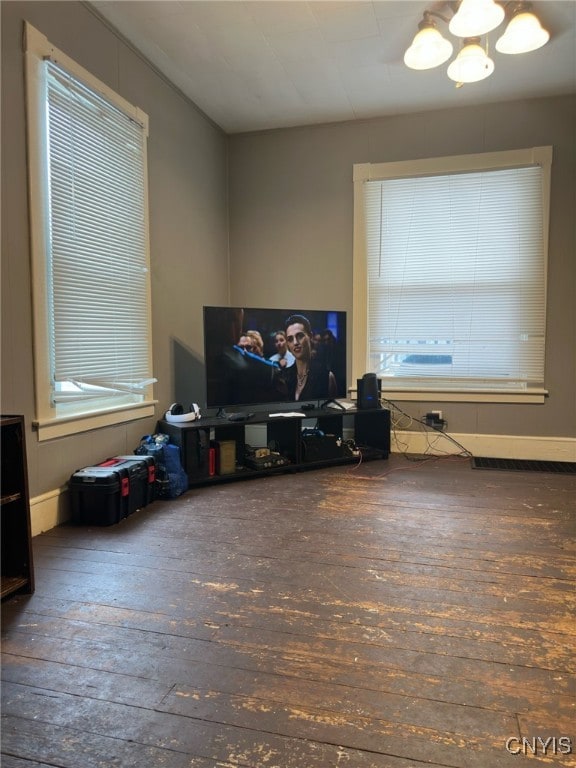 living room with a healthy amount of sunlight, an inviting chandelier, and dark hardwood / wood-style flooring