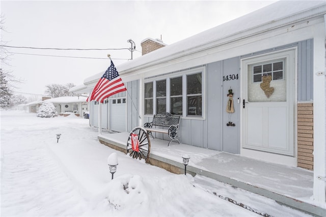 snow covered property entrance with a garage