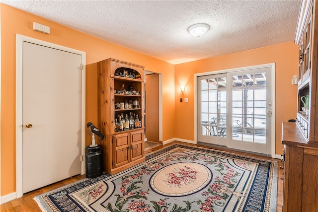 doorway to outside featuring a textured ceiling and light hardwood / wood-style flooring