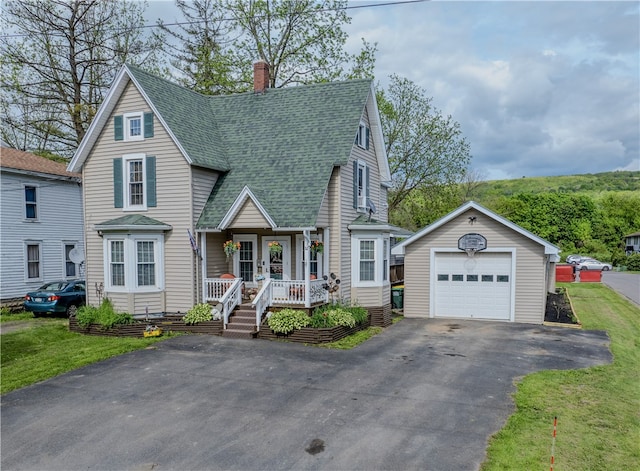 view of front of house featuring a front yard, covered porch, an outdoor structure, and a garage