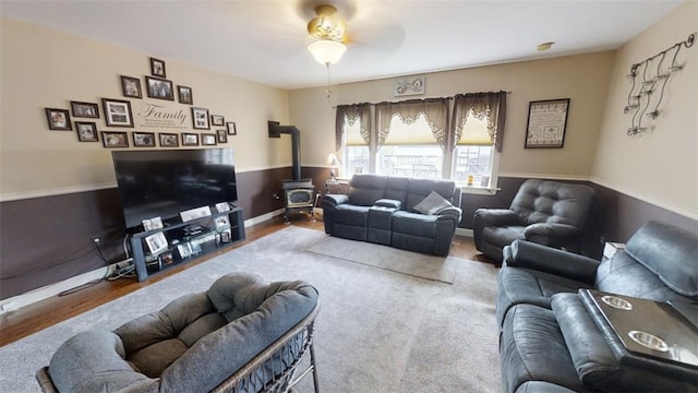 living room featuring ceiling fan, a wood stove, and wood-type flooring