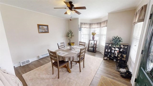 dining area with ceiling fan, a baseboard radiator, hardwood / wood-style floors, and crown molding