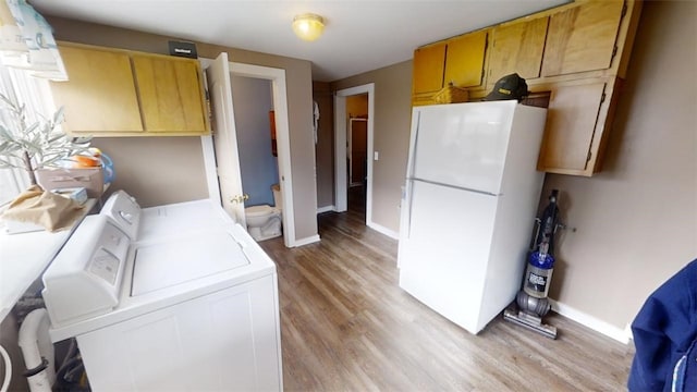 washroom with light wood-type flooring, washer and dryer, and cabinets