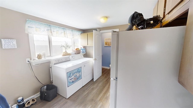 laundry room with light wood-type flooring, independent washer and dryer, and cabinets