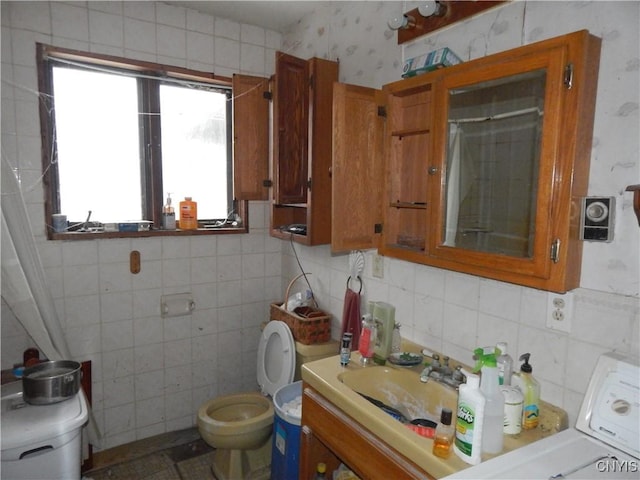 bathroom featuring toilet, tile walls, backsplash, and vanity