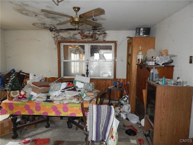 misc room featuring ceiling fan and wood walls