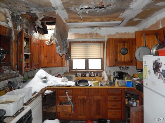 kitchen featuring tasteful backsplash, gas range oven, sink, and white refrigerator