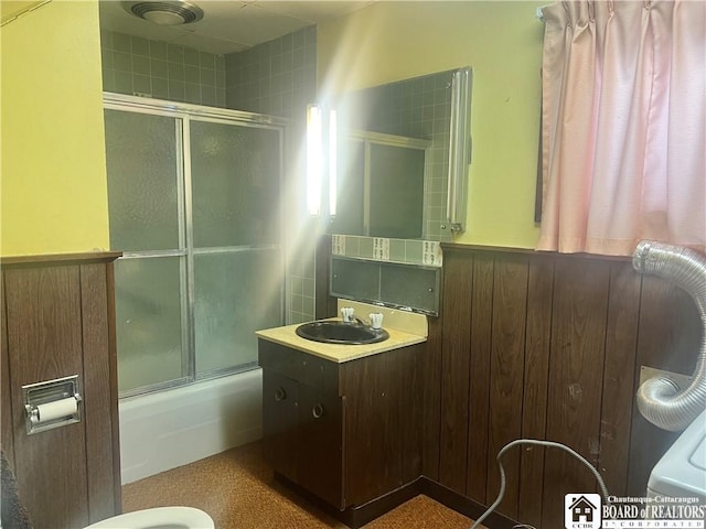 bathroom featuring shower / bath combination with glass door, vanity, and wooden walls