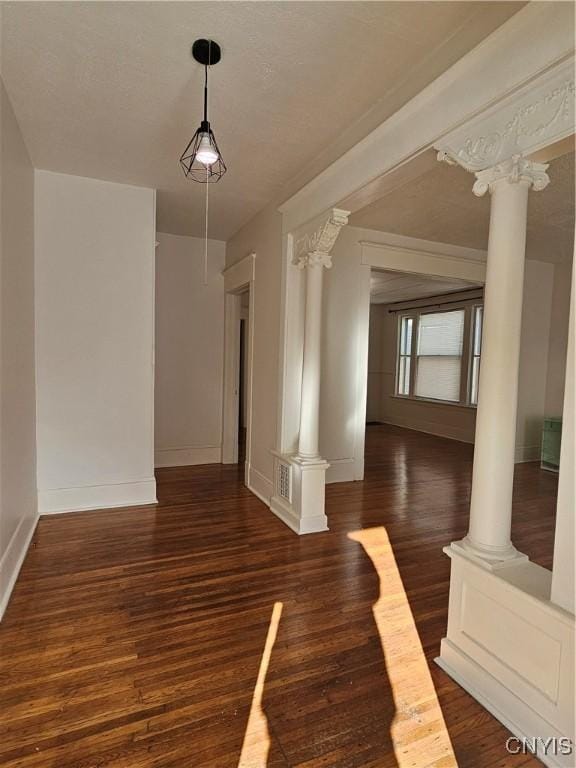 interior space with decorative columns and dark hardwood / wood-style floors