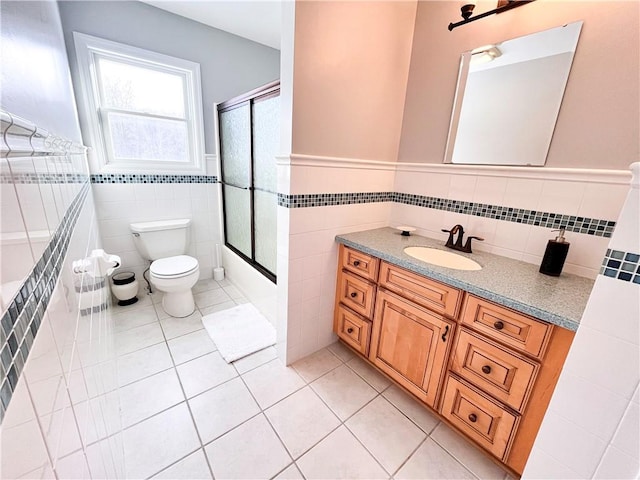 full bathroom with toilet, vanity, tile patterned flooring, tile walls, and shower / bath combination with glass door