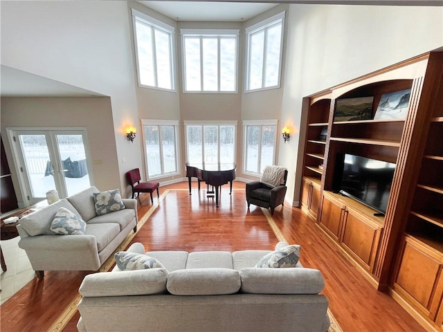 living room with french doors, built in features, plenty of natural light, and light hardwood / wood-style flooring