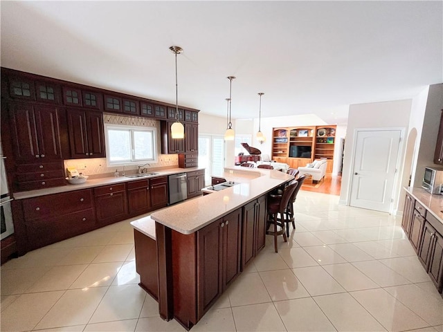 kitchen featuring decorative light fixtures, a kitchen island, stainless steel dishwasher, sink, and light tile patterned floors