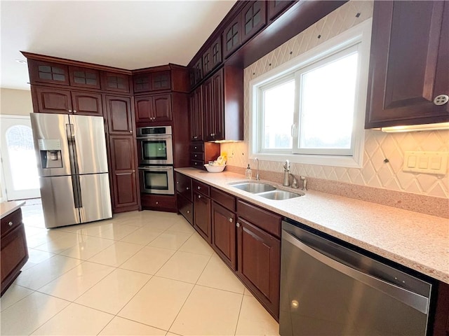 kitchen with light tile patterned flooring, stainless steel appliances, decorative backsplash, and sink