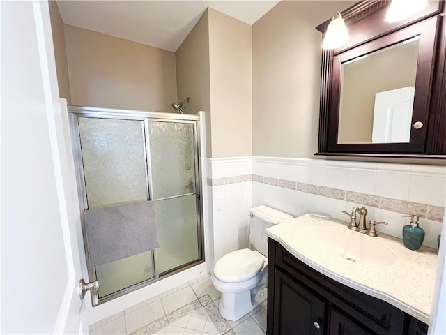 bathroom featuring toilet, tile walls, a shower with shower door, and vanity