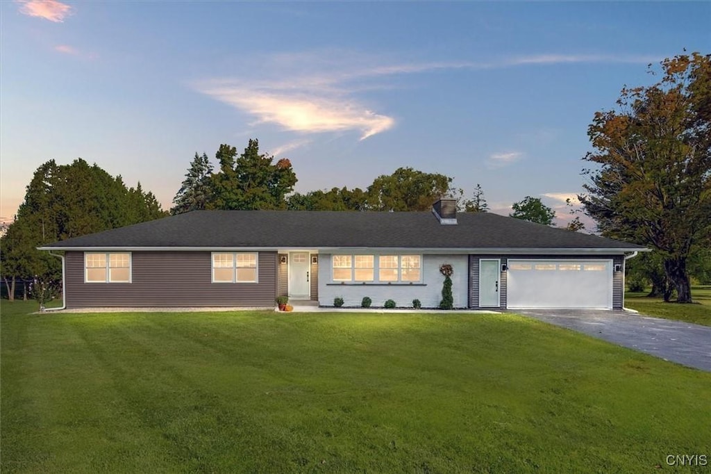 single story home with a garage and a lawn