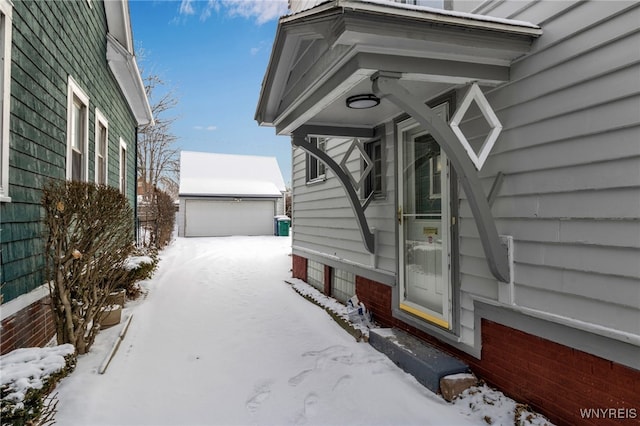 snow covered property featuring a garage and an outdoor structure