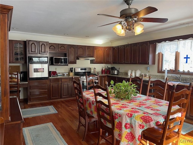 dining area with dark wood-type flooring, ornamental molding, and ceiling fan