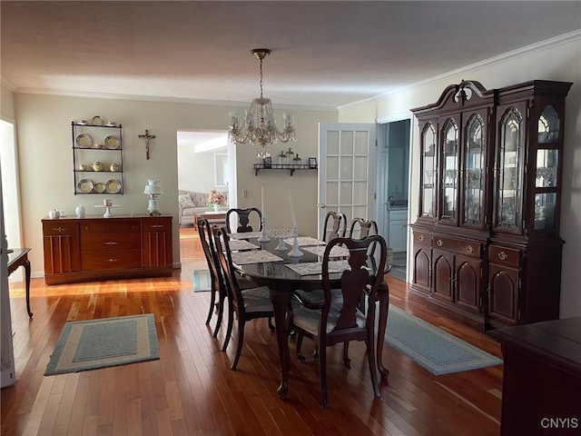 dining area featuring hardwood / wood-style flooring, ornamental molding, and a notable chandelier