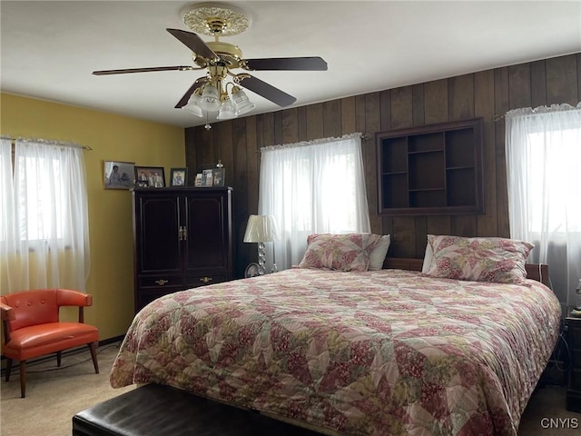 bedroom with ceiling fan, carpet flooring, and wooden walls