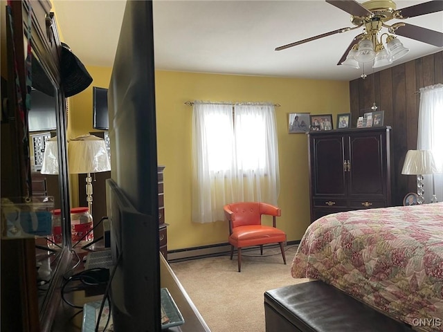 bedroom with ceiling fan, carpet, wooden walls, and multiple windows