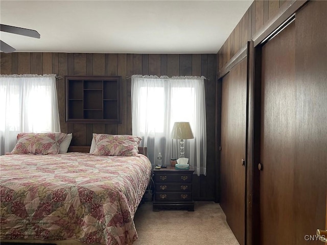 carpeted bedroom featuring ceiling fan and wooden walls