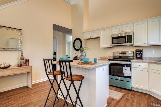 kitchen featuring a kitchen bar, dark wood-type flooring, white cabinetry, and stainless steel appliances