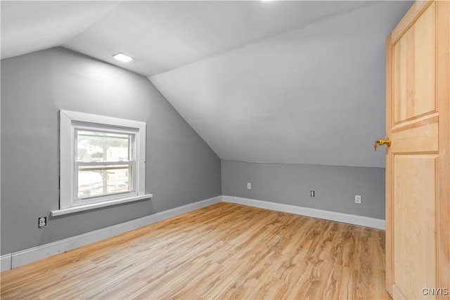 additional living space featuring light wood-type flooring and vaulted ceiling