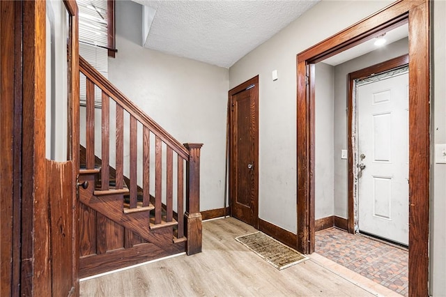 foyer entrance featuring light hardwood / wood-style floors and a textured ceiling