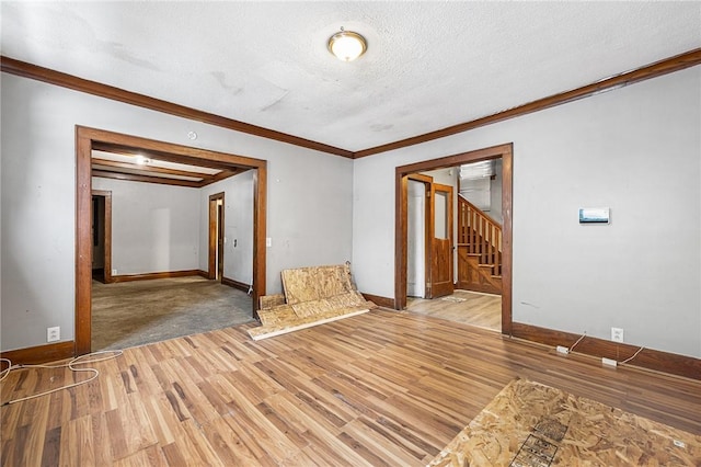 unfurnished room with a textured ceiling, ornamental molding, and light hardwood / wood-style floors