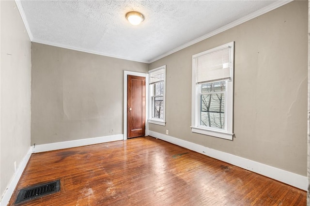 unfurnished room with a textured ceiling, crown molding, and wood-type flooring