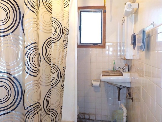 bathroom with sink, backsplash, and tile walls