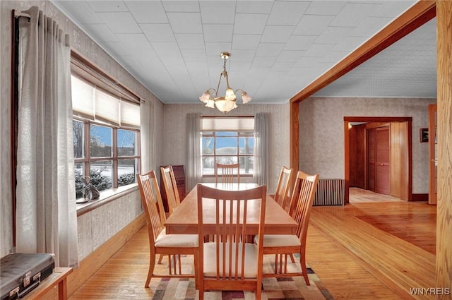 dining area with light hardwood / wood-style floors, a wealth of natural light, and a chandelier