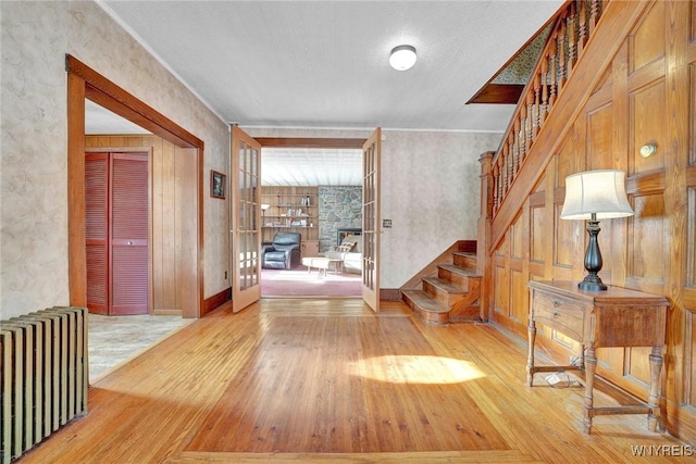 foyer entrance with radiator, light hardwood / wood-style flooring, and a stone fireplace