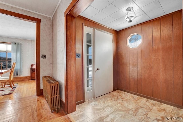 entryway with radiator, wood walls, and crown molding