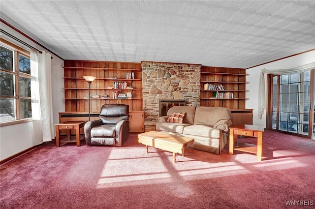 carpeted living room featuring built in features, a stone fireplace, and ornamental molding