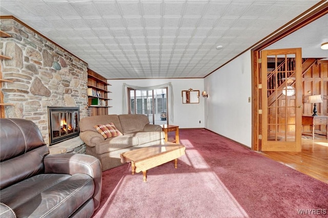 carpeted living room with ornamental molding and a stone fireplace