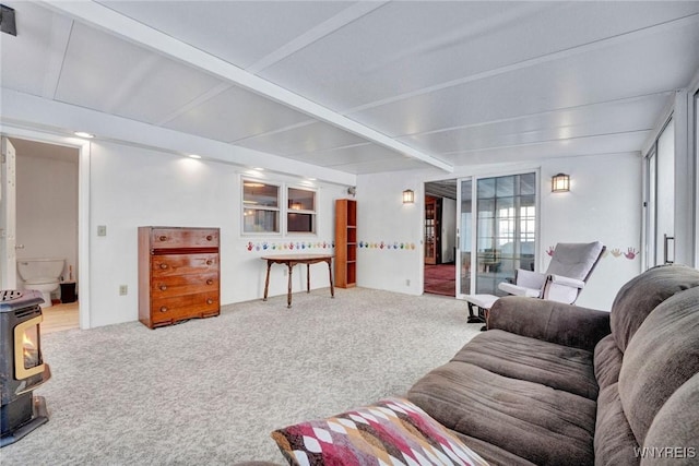 living room with plenty of natural light, beamed ceiling, a wood stove, and carpet flooring