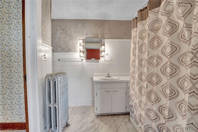 bathroom featuring a textured ceiling, radiator heating unit, and vanity