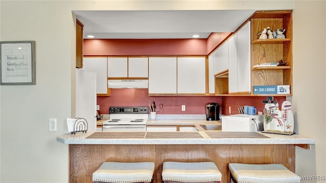 kitchen with a breakfast bar, white appliances, white cabinets, and sink