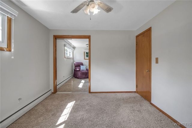 carpeted empty room featuring ceiling fan and a baseboard heating unit