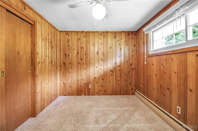 carpeted spare room with ceiling fan, wooden walls, and a baseboard radiator