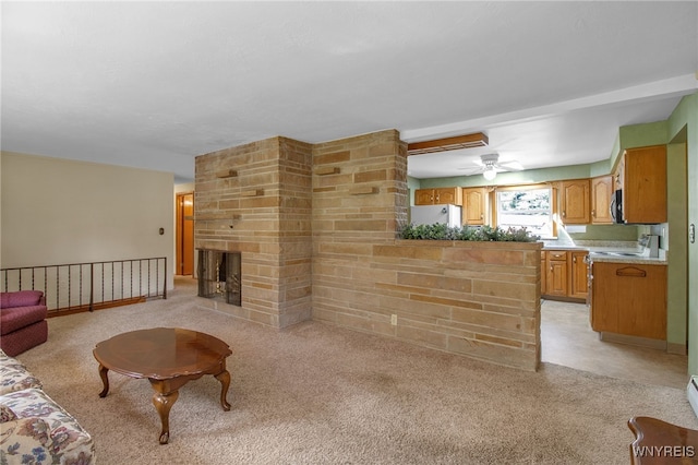 carpeted living room with ceiling fan and a stone fireplace