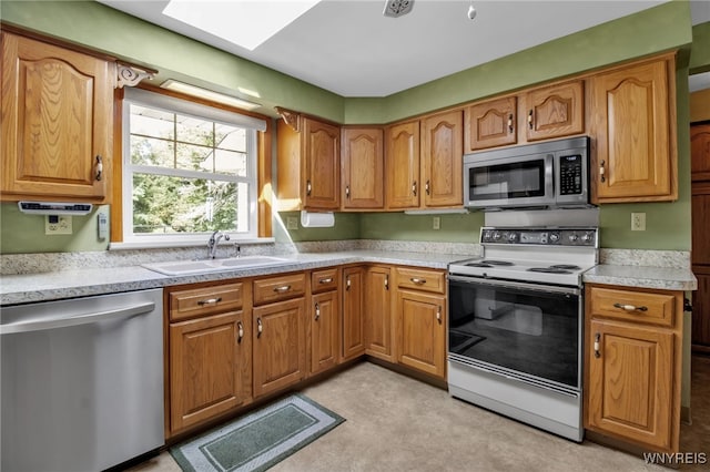 kitchen featuring a skylight, stainless steel appliances, and sink